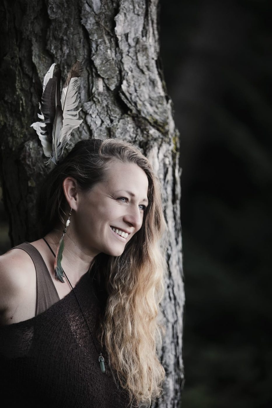 Linda Arent lacht, an einen Baum gelehnt